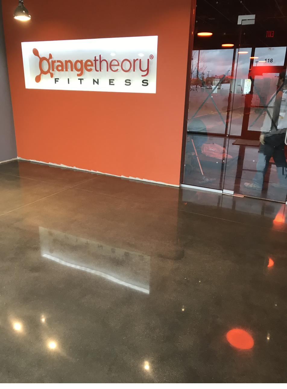 Polished dark concrete floor at an Orangetheory Fitness entrance